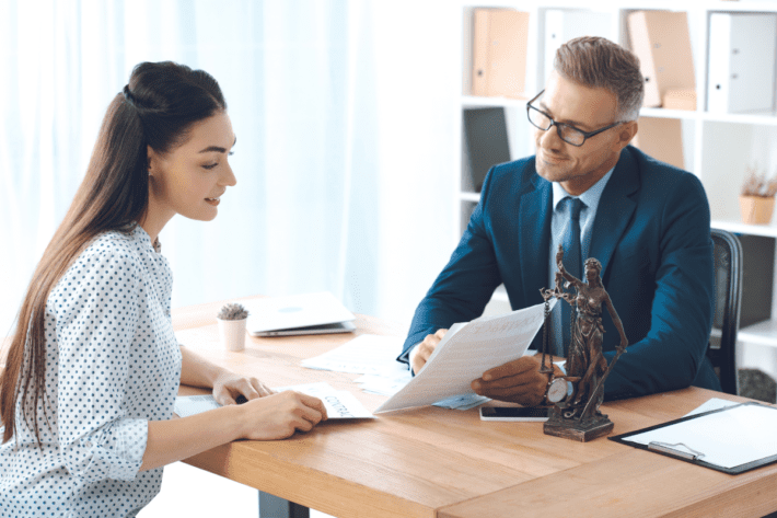 Um homem está explicando um contrato de empréstimo para uma mulher, destacando os detalhes importantes sobre as taxas de juros. A cena reflete a importância de entender os termos antes de assinar qualquer documento financeiro, ajudando a evitar surpresas e como lidar com juros abusivos.