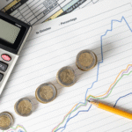 Calculadora ao lado de moedas e gráficos, simbolizando o acompanhamento do PIB e o planejamento financeiro.