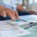 Homem usando calculadora para calcular investimentos e entender o impacto da taxa CDI no seu dinheiro.
